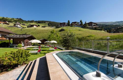 a swimming pool with a view of a house at Hotel Alpin Spa Tuxerhof in Tux