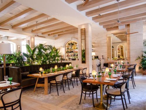 Browns Avenue Hotel في لشبونة: مطعم بطاولات خشبية وكراسي ونباتات