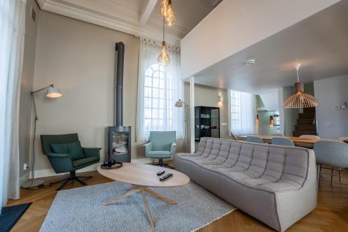 uma sala de estar com um sofá, uma mesa e cadeiras em Nobel - Suites em Ballum