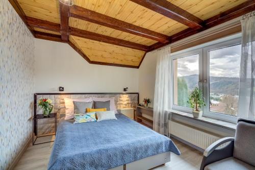 a bedroom with a blue bed and a window at Pokoje Gościnne Mena in Muszyna