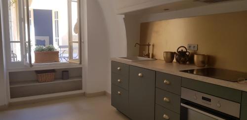 kuchnia z blatem, umywalką i oknem w obiekcie Jolie maison de ville La Petite Magnanerie w mieście La Roque-dʼAnthéron