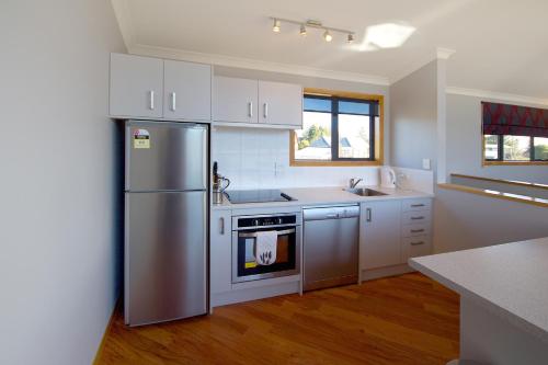 una cocina con nevera de acero inoxidable y armarios blancos en Parkview Apartments, en National Park