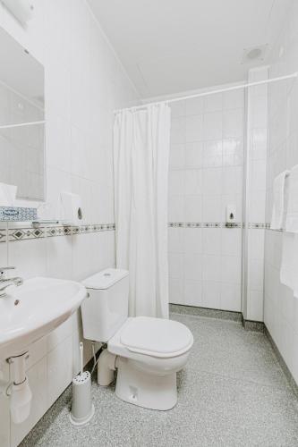 a white bathroom with a toilet and a sink at Narfastadir Guesthouse in Laugar