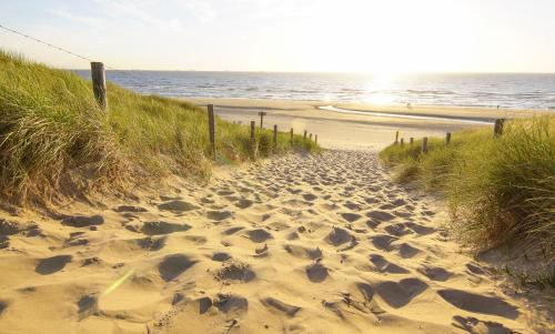 a sandy beach with footprints in the sand and the ocean at Vakantiepark Koningshof in Rijnsburg