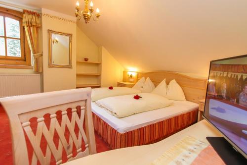 a bedroom with a bed and a desk with a television at Dandler - Zimmer und Ferienwohnungen in Fieberbrunn