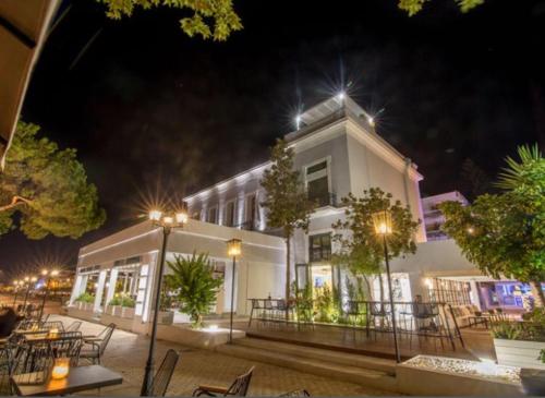 a white building with tables and chairs at night at Panellinion Luxury Rooms in Kalamata