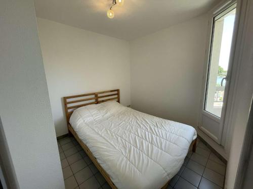 a small bed in a room with a window at Deux pièces rénové avec terrasse, parking privé à Port Camargue - FR-1-250-173 in Saint-Mélany