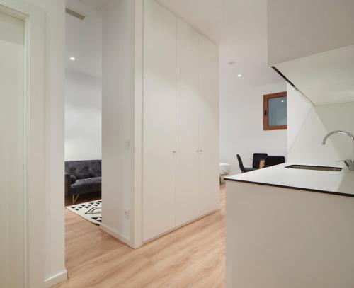 a kitchen and living room with white walls and wood floors at Hotel Iriguibel Huarte Pamplona in Huarte