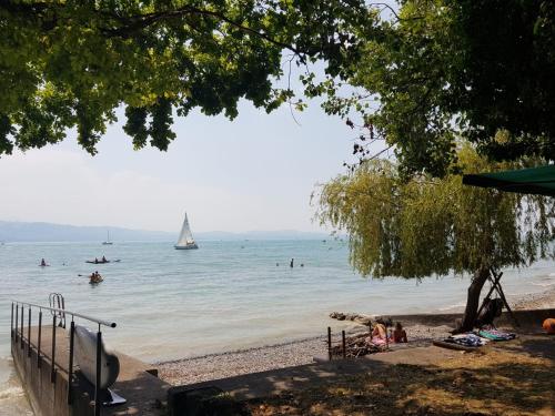 una playa con gente nadando y un velero en el agua en Ferienhaus Rebhof, en Nonnenhorn