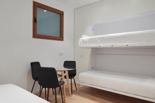 a bedroom with bunk beds and a table and chairs at Hotel Iriguibel Huarte Pamplona in Huarte