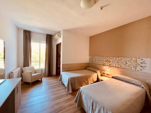 una habitación de hotel con 2 camas y una silla en Hotel Balneario Fuentes del Trampal, en Carmonita