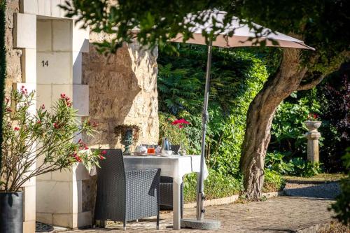 a table with an umbrella in a garden at Le Pavillon des Lys - Hôtel Particulier in Amboise