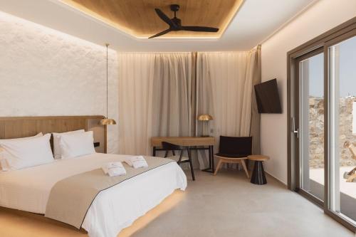 a bedroom with a bed and a desk and a window at Calma Suites Mykonos in Psarou