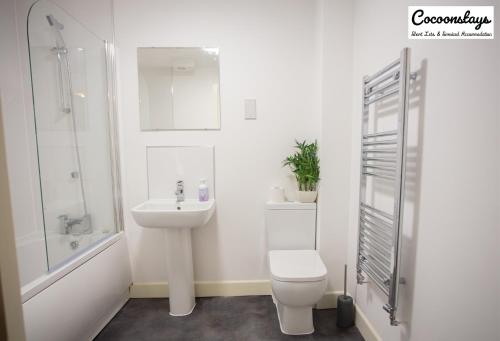 Baño blanco con aseo y lavamanos en Cocooonstays Stays Short Lets & Serviced Accommodation Slough, en Slough