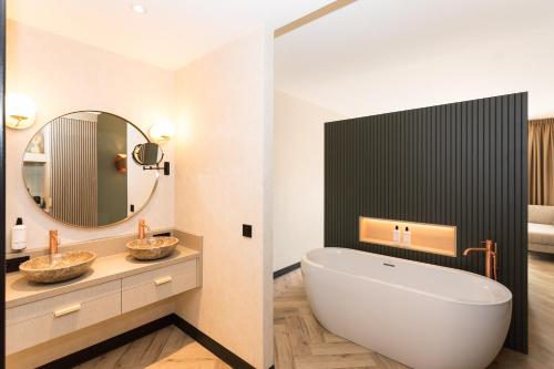 a bathroom with a tub and a sink and a mirror at Boutique Hotel Helder I Kloeg Collection in Renesse
