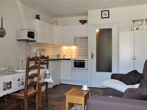 une cuisine avec des armoires blanches et une table dans une pièce dans l'établissement Studio 4 couchages au pied des pistes avec casier à ski, Risoul 1850 - FR-1-330-156, à Risoul