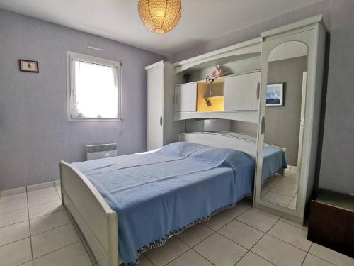 une chambre avec un lit bleu et un miroir dans l'établissement Carnac - Appartement 2 pièces avec terrasse, piscine et parking privé, à 400m de la plage. - FR-1-477-123, à Carnac