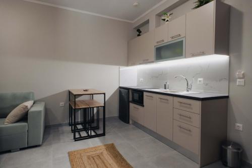 a kitchen with white cabinets and a sink and a couch at Savere luxury studios in Skiathos Town