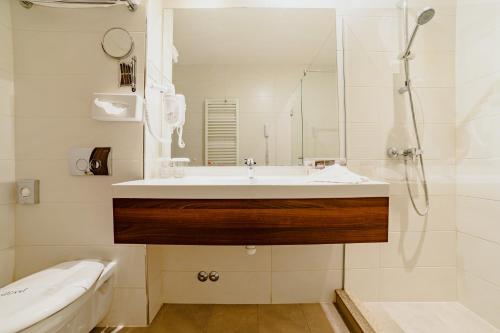 a white bathroom with a sink and a shower at Radsor Hotel in Râşnov