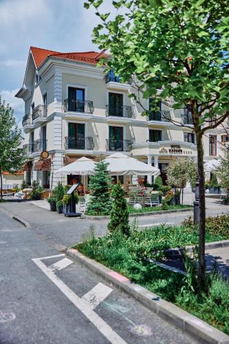a large white building with tables and umbrellas at Radsor Hotel in Râşnov