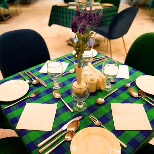 a table with a green and purple table cloth with plates and silverware at Indigo Heights Hotel & Suites in Lahore