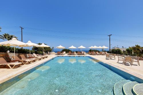 a swimming pool with lounge chairs and umbrellas at Marni Village in Hersonissos