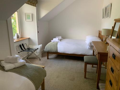 a bedroom with two beds and a desk and a chair at Cameron Cottage in Inverkip
