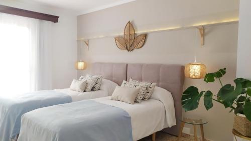 two beds with white sheets and a plant in a room at Hotel Nou Can Guillem in Cala Figuera