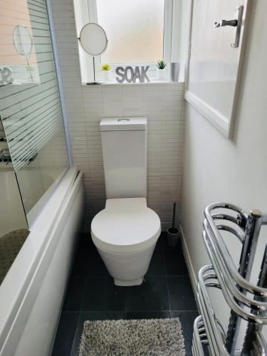 a small bathroom with a toilet and a bath tub at Primrose House in Whitefield