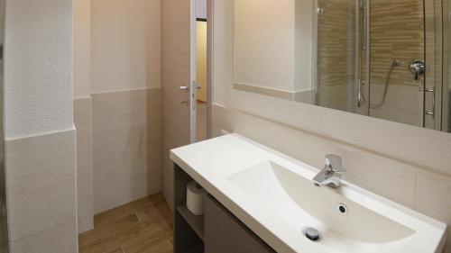 La salle de bains est pourvue d'un lavabo blanc et d'un miroir. dans l'établissement Welcomely - Villa Paola B, à Costa Rei