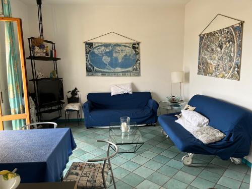 sala de estar con 2 sofás azules y TV en Casetta Sirenetta, en Castiglione della Pescaia