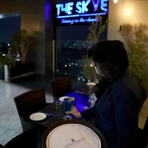 a person wearing a mask sitting at a table in a restaurant at Indigo Heights Hotel & Suites in Lahore