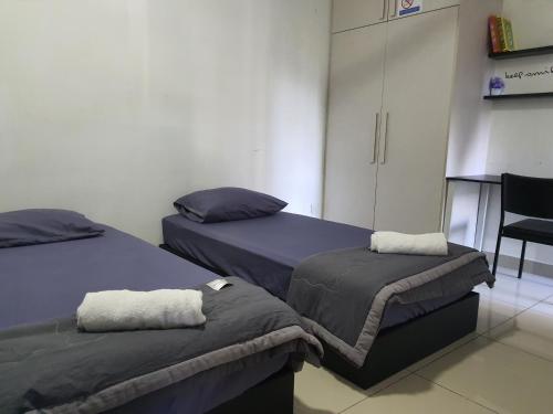 sypialnia z 2 łóżkami i krzesłem w obiekcie Dwiputra Presint 15 at Putrajaya w mieście Putrajaya