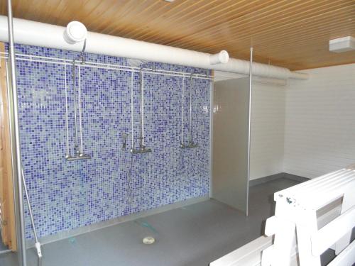 uma casa de banho com chuveiro e azulejos azuis na parede em Kuhasensaari Lomakeskus em Lemi