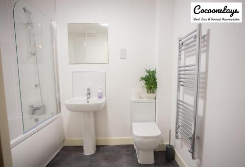 a white bathroom with a toilet and a sink at Cocooonstays Short Lets & Accommodation Slough in Slough