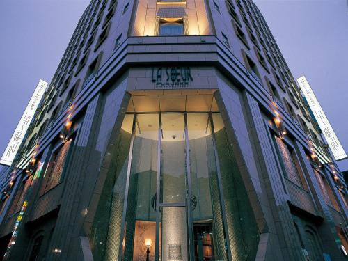 a tall building with a clock on top of it at Hotel Monterey La Soeur Fukuoka in Fukuoka