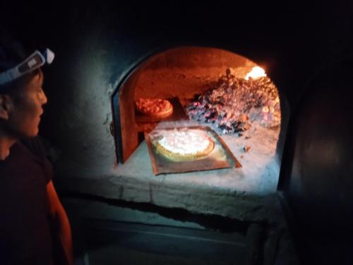 a person looking at a pizza in a brick oven at Ecolodge Casa del Montañista in Huaraz