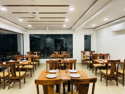 Un comedor con mesas y sillas de madera. en Hotel Akoya - HITECH City Hyderabad, en Hyderabad