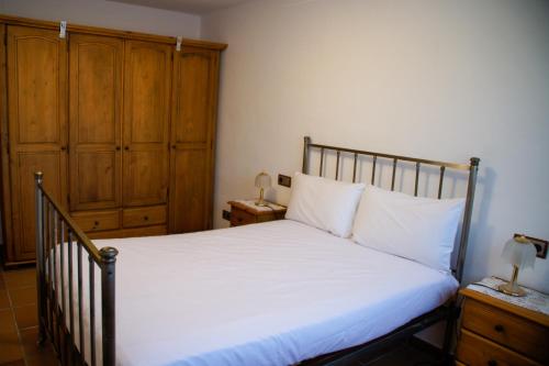 a bedroom with a bed with white sheets and wooden cabinets at Casa Martina in Cardedeu