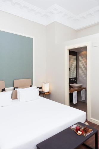 a white bedroom with a bed and a table at Hotel Sardinero Madrid in Madrid