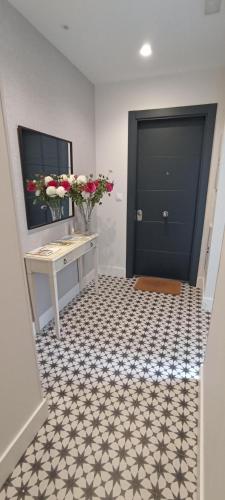 a hallway with a black door and a desk with flowers at La Rua 25 in Castro-Urdiales