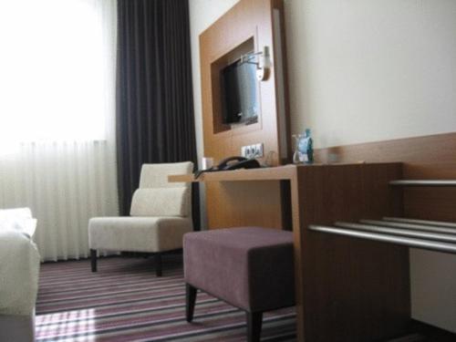 um quarto de hotel com uma cadeira e uma televisão em Qualitel Hilpoltstein em Hilpoltstein