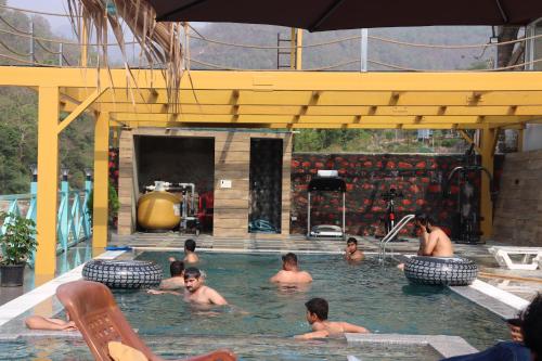 een groep mensen die zwemmen in een zwembad bij MR River Resort in Rishīkesh