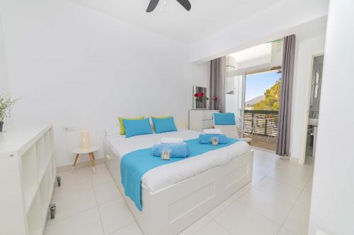 a white bedroom with a large bed with blue pillows at Apartamento Xara in Alcudia