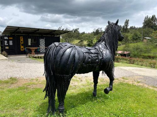 a statue of a horse is standing in the grass at Acogedor y moderno Glamping en container, 10 min del centro in Chiquinquirá