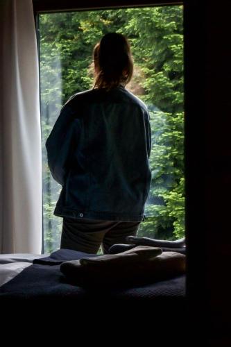 a person standing looking out of a window at Novosiele Residence - nad górską rzeką - Leśne Spa sauna jacuzzi - Bieszczady in Bystre