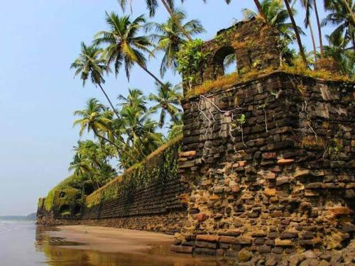 an old stone wall on the beach with palm trees at Parvati Niwas Homestay -Nearby Revdanda Beach & Fort - WiFi available in Alibaug