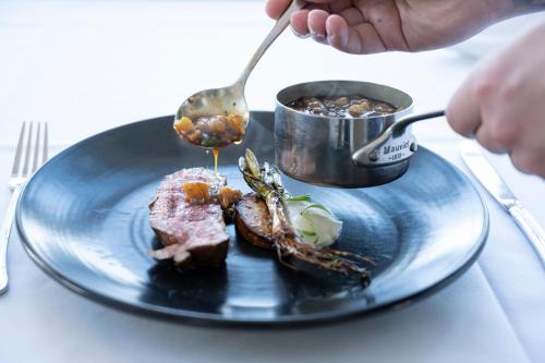 a plate of food with a piece of meat and a spoon at Stammershalle Badehotel in Bådsted