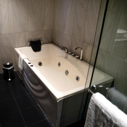 a bath tub in a bathroom with a glass wall at Indigo Heights Hotel & Suites in Lahore