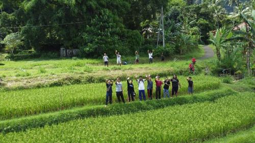 a group of people standing in a field at Mojito Beach Villas in Kubutambahan